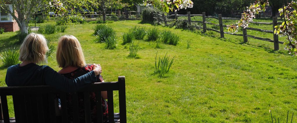 Two woman sat on bench looking into distance